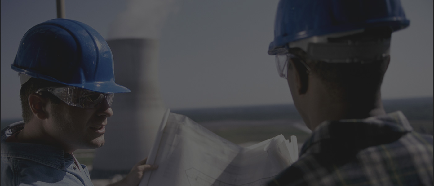 A man in hard hat holding papers and looking at something.