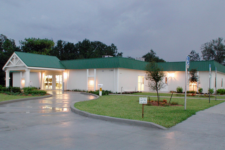 A large white building with green roof and grass.