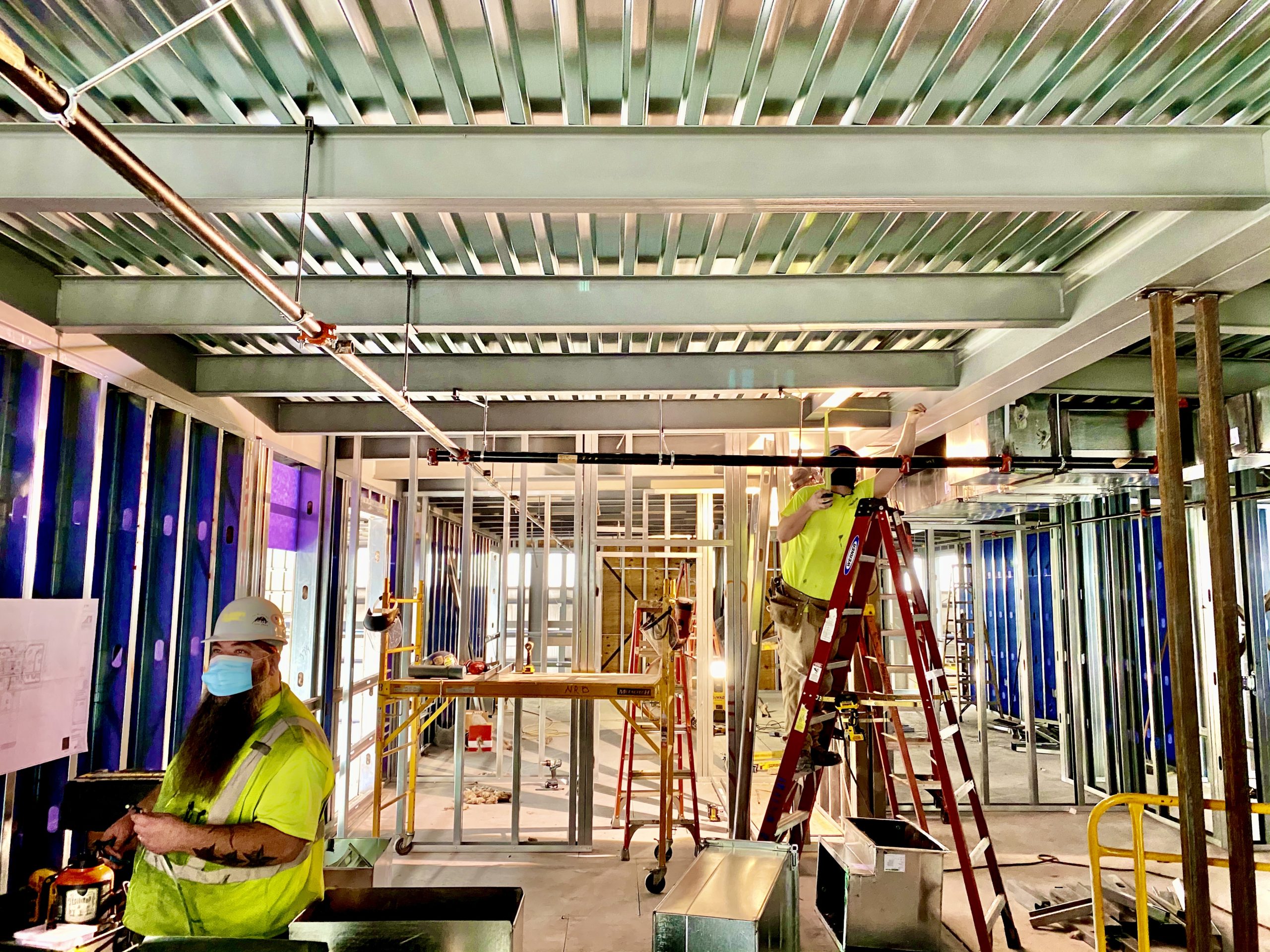 A group of construction workers working on the ceiling.